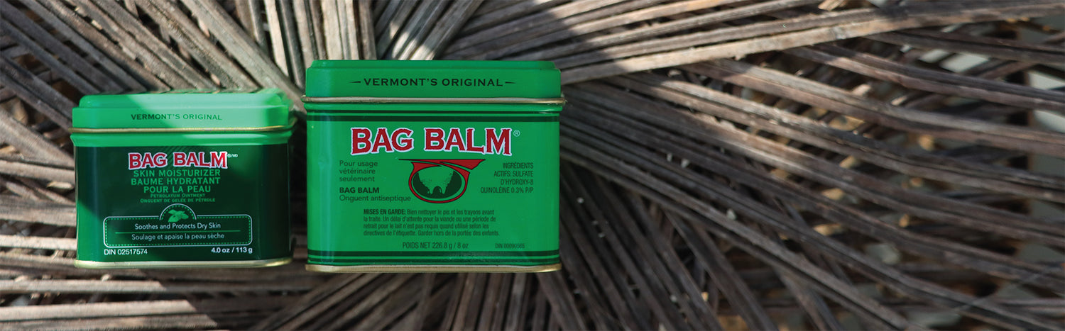 An image of Bag Balm, a moisturizing balm in a green tin, set against a wicker background. The tin features the Bag Balm logo and a depiction of a cow, highlighting its heritage as a product originally used for cow udders.